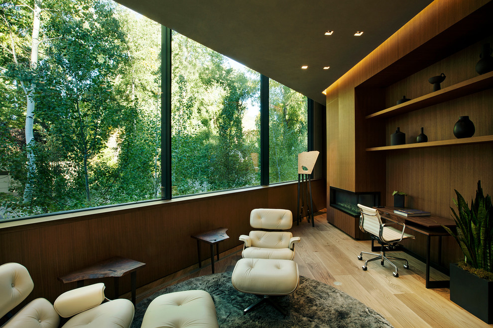 デンバーにあるコンテンポラリースタイルのおしゃれなホームオフィス・書斎 (茶色い壁、淡色無垢フローリング、両方向型暖炉、自立型机、ベージュの床) の写真