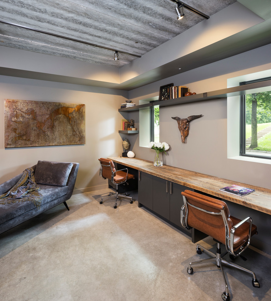 Diseño de despacho moderno pequeño con paredes beige, suelo de cemento y escritorio empotrado