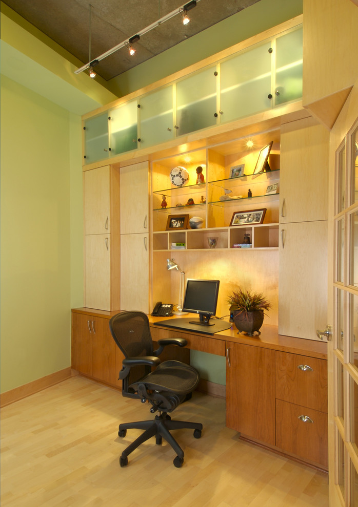 На фото: кабинет в современном стиле с зелеными стенами, паркетным полом среднего тона и встроенным рабочим столом с