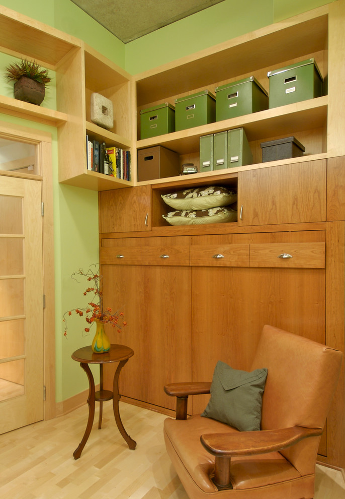 Modern inredning av ett arbetsrum, med gröna väggar och ljust trägolv