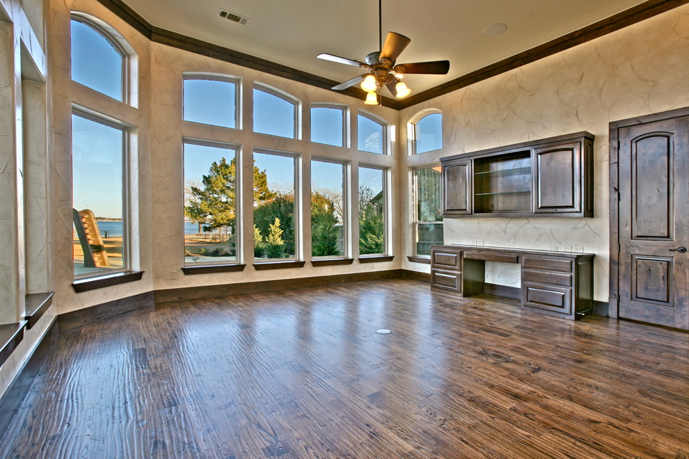 Photo of a large mediterranean study in Dallas with beige walls, dark hardwood flooring and a built-in desk.