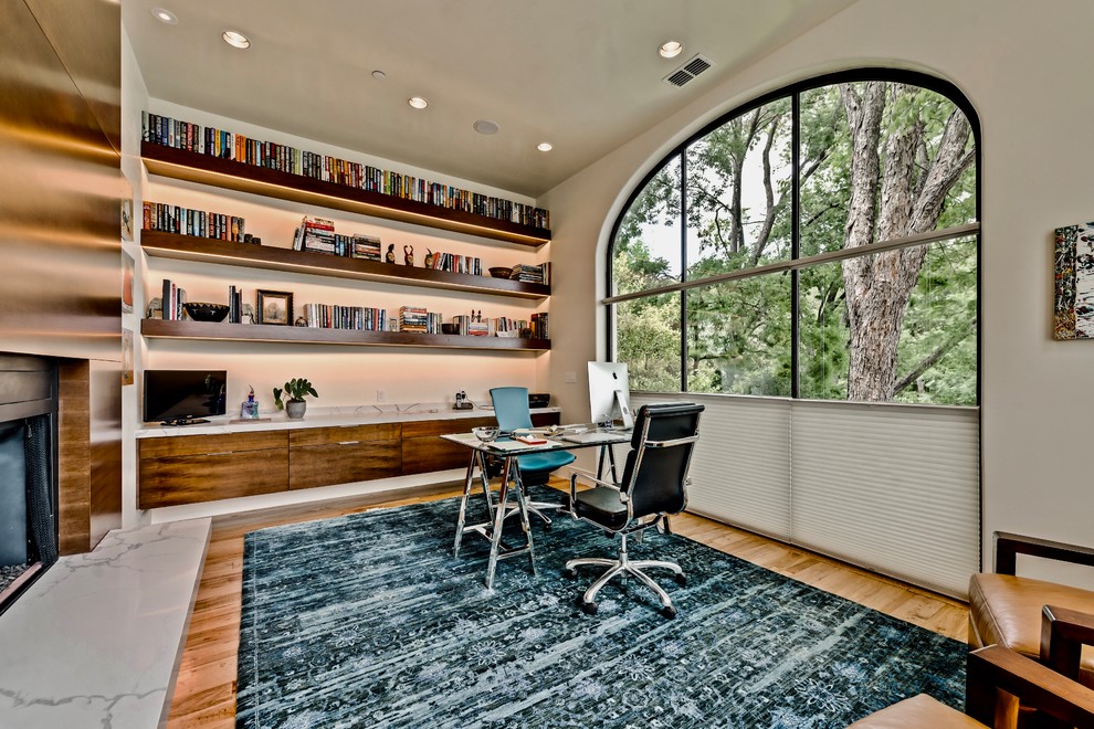 Inspiration för ett stort vintage hemmabibliotek, med grå väggar, mellanmörkt trägolv, en bred öppen spis, en spiselkrans i trä och ett fristående skrivbord