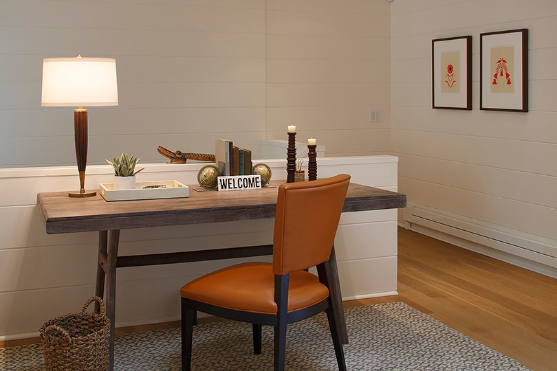 Diseño de despacho rústico grande con paredes blancas, suelo de madera clara y escritorio independiente