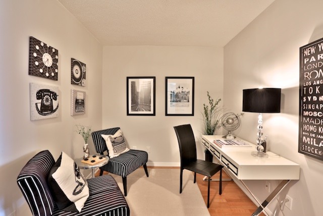 Small contemporary home studio in Toronto with beige walls, medium hardwood flooring, a freestanding desk, no fireplace and beige floors.