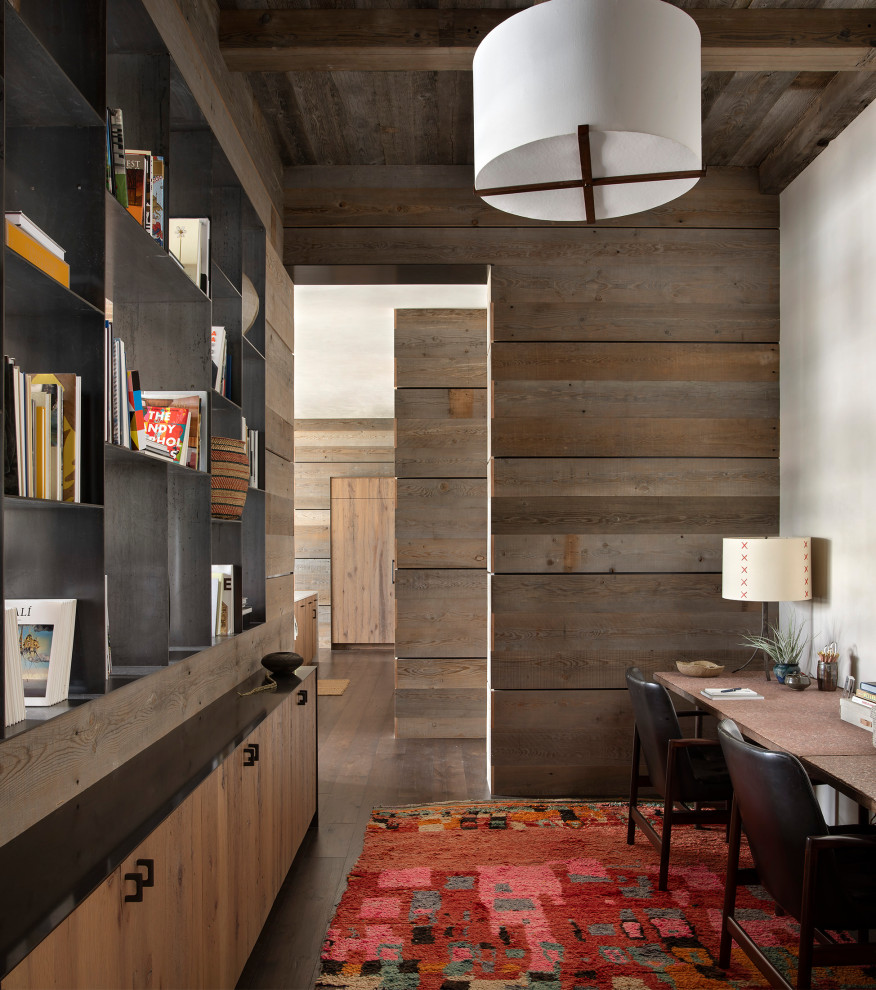 Uriges Arbeitszimmer mit Arbeitsplatz, brauner Wandfarbe, braunem Holzboden, freistehendem Schreibtisch und braunem Boden in Sonstige