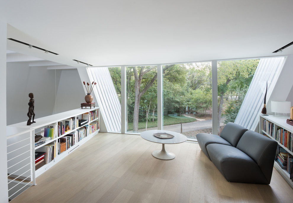 Inspiration for a modern study in Austin with white walls and light hardwood flooring.