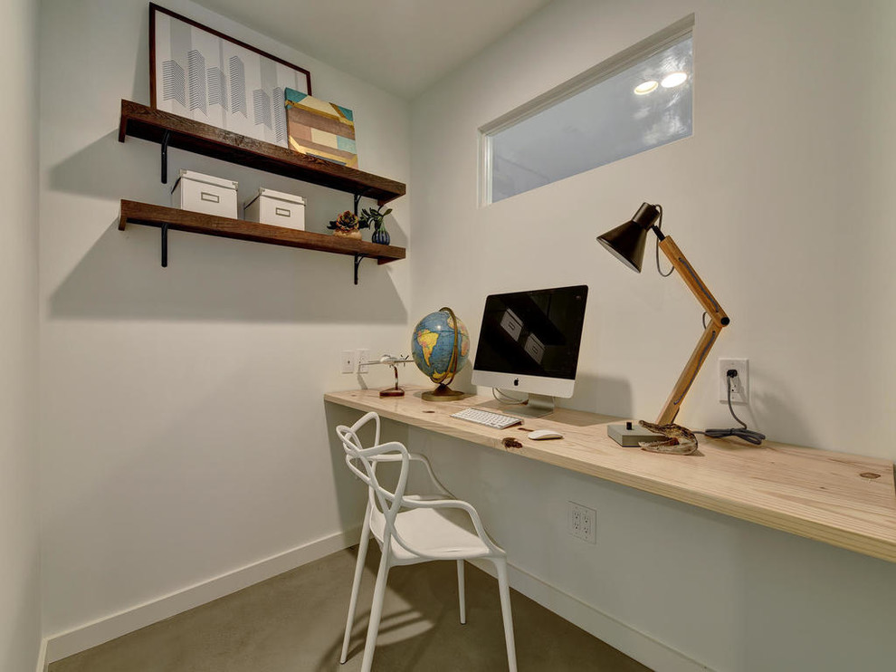 Home office - small modern built-in desk concrete floor home office idea in Austin with white walls
