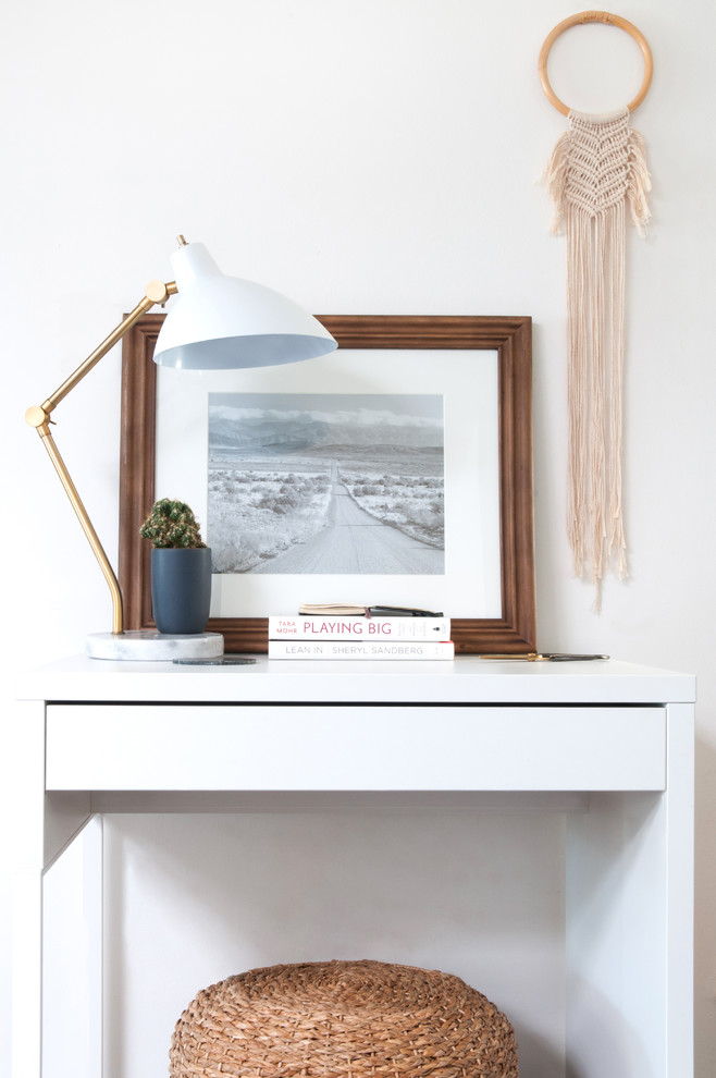 Foto på ett stort minimalistiskt arbetsrum, med vita väggar, heltäckningsmatta, ett fristående skrivbord och svart golv