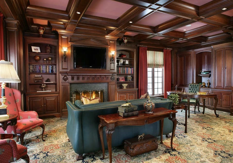 Imagen de despacho clásico grande con paredes marrones, moqueta, todas las chimeneas, marco de chimenea de piedra y escritorio independiente