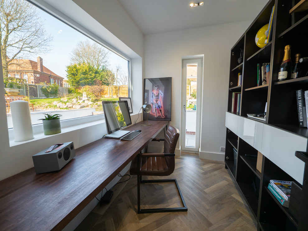 Kleines Modernes Arbeitszimmer mit Arbeitsplatz, weißer Wandfarbe, hellem Holzboden, Einbau-Schreibtisch und braunem Boden in West Midlands
