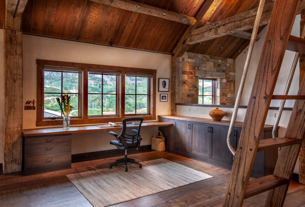 Photo of a large rustic study in Denver with a built-in desk, brown floors, white walls and medium hardwood flooring.