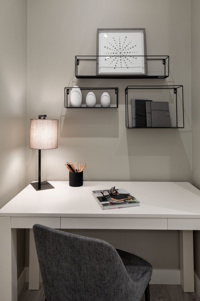Modern inredning av ett litet arbetsrum, med beige väggar, heltäckningsmatta, ett fristående skrivbord och beiget golv