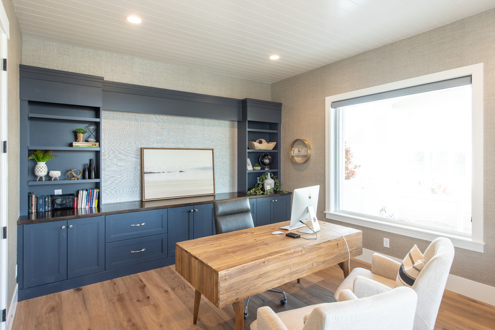 Large classic study in Salt Lake City with grey walls, light hardwood flooring, no fireplace, a freestanding desk and beige floors.