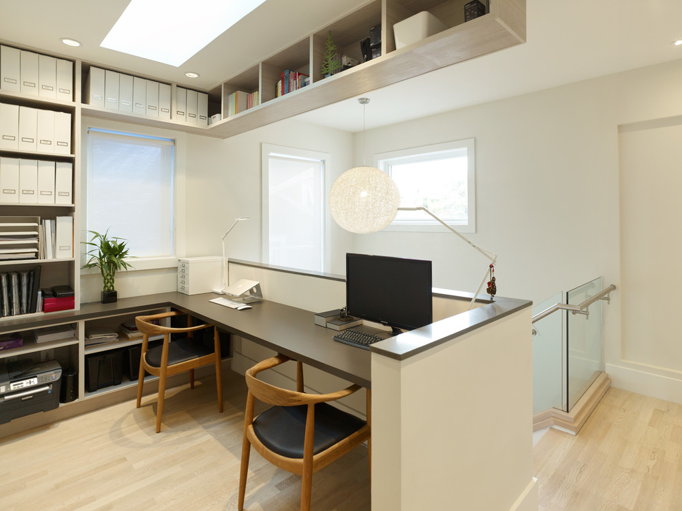 Ejemplo de despacho actual pequeño sin chimenea con paredes blancas, suelo de madera clara y escritorio empotrado