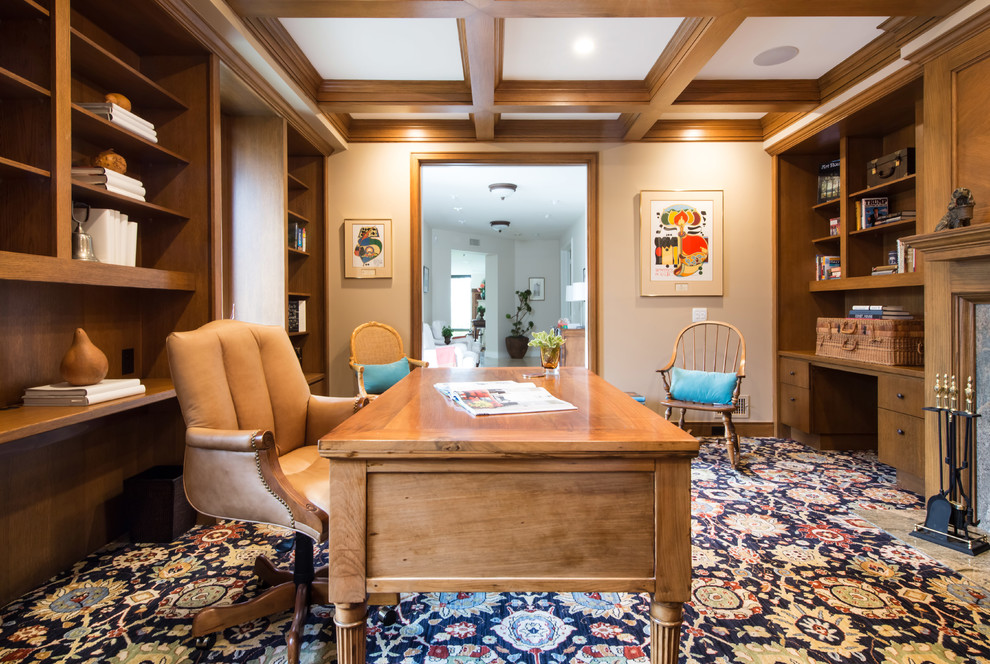 Ispirazione per un grande studio tradizionale con libreria, pareti beige, pavimento in legno massello medio, scrivania autoportante e pavimento marrone