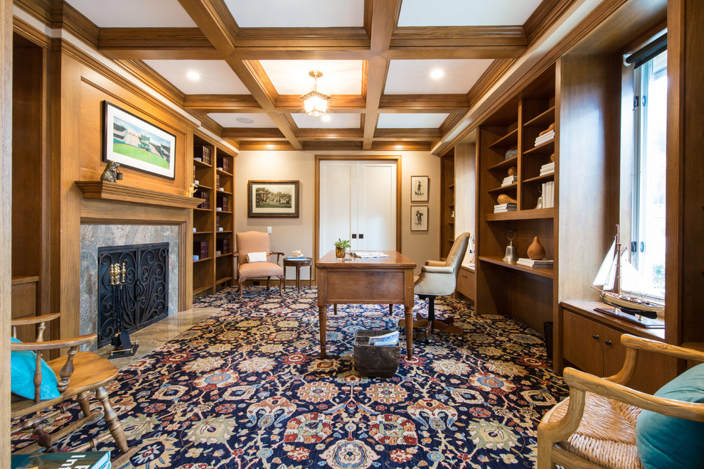 Großes Klassisches Lesezimmer mit beiger Wandfarbe, Teppichboden, Kamin, Kaminumrandung aus Stein, freistehendem Schreibtisch und buntem Boden in San Diego