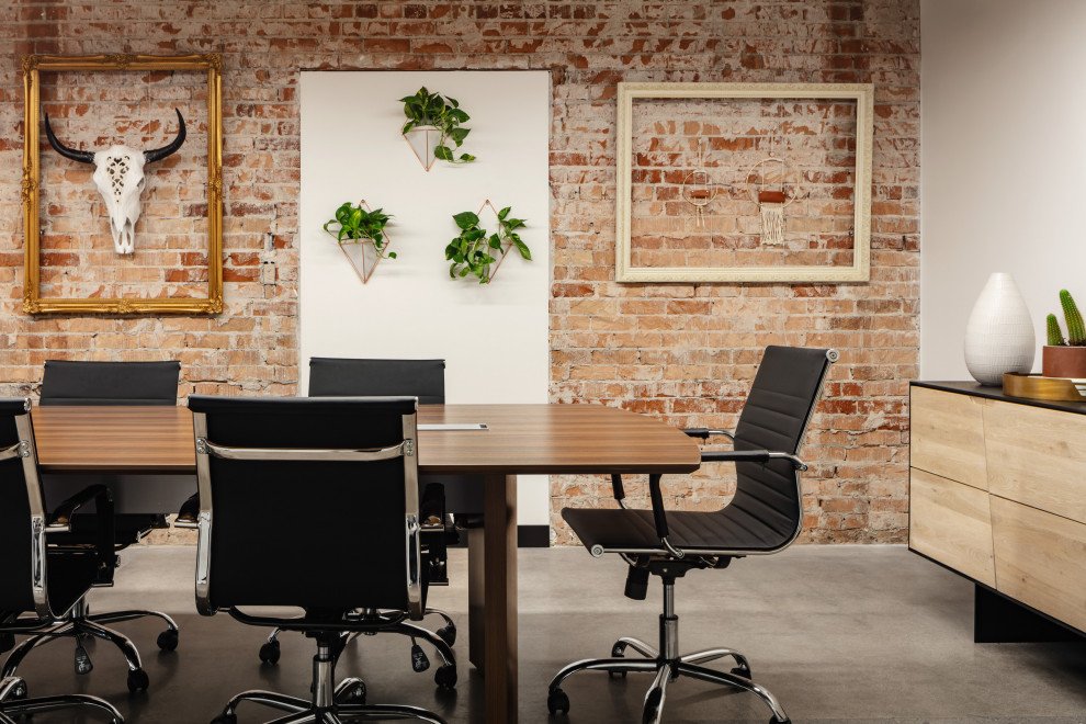 Foto på ett amerikanskt arbetsrum, med bruna väggar, betonggolv, ett fristående skrivbord och grått golv