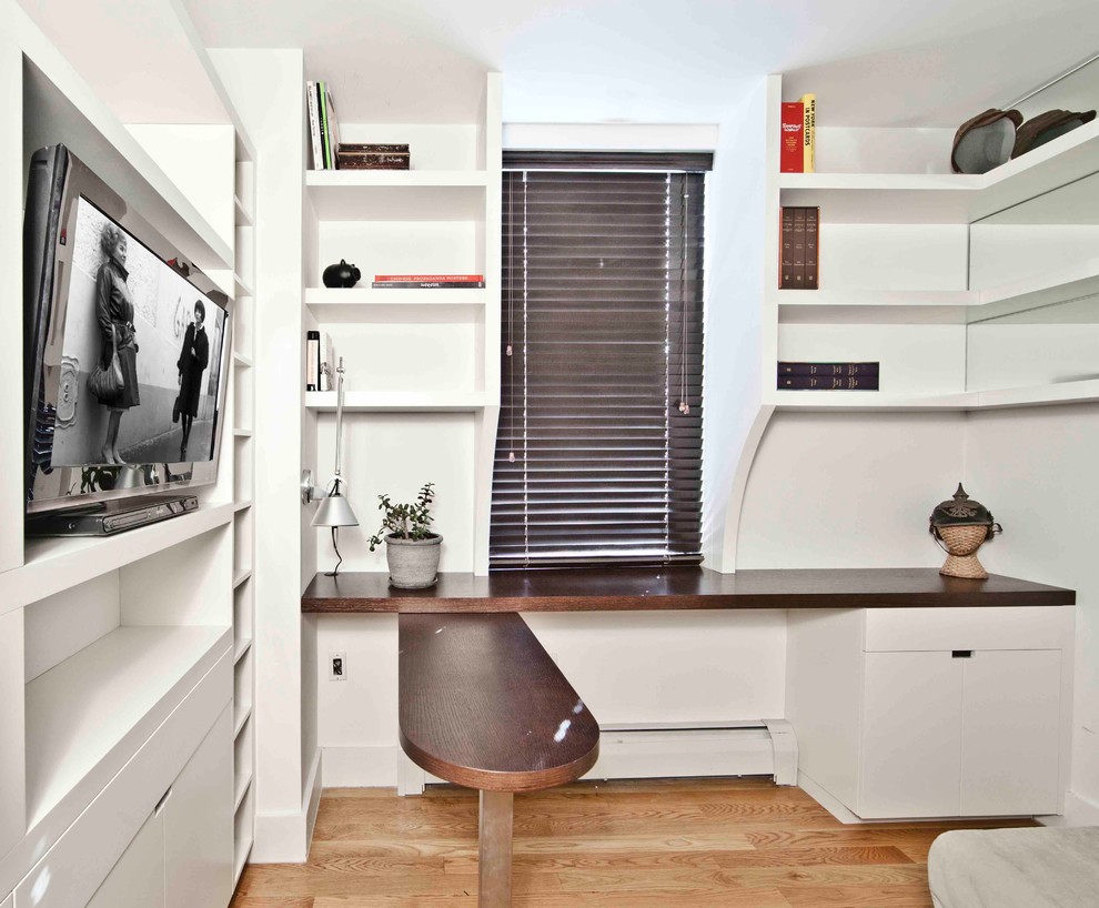 Modern inredning av ett arbetsrum, med vita väggar, mellanmörkt trägolv och ett inbyggt skrivbord