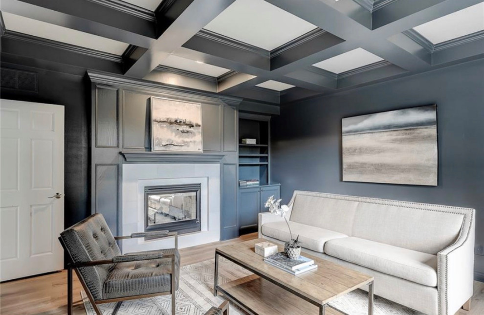 Ejemplo de despacho clásico renovado de tamaño medio con paredes azules, suelo de madera clara, chimenea de doble cara, marco de chimenea de piedra y suelo beige
