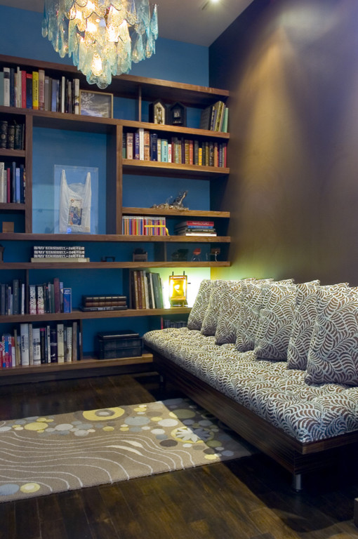 Immagine di uno studio moderno di medie dimensioni con libreria, pareti blu e parquet scuro