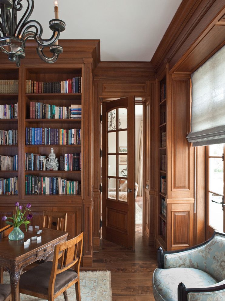 Diseño de despacho tradicional de tamaño medio con biblioteca, paredes marrones, suelo de madera oscura, escritorio independiente y suelo marrón