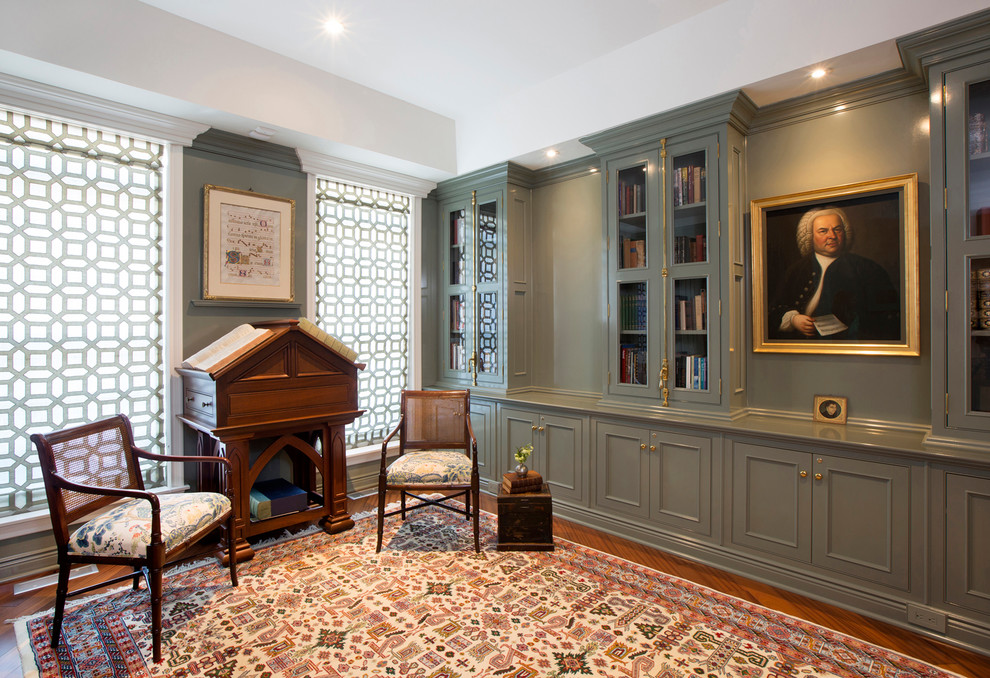 Mittelgroßes Klassisches Lesezimmer mit grüner Wandfarbe, braunem Holzboden, freistehendem Schreibtisch und braunem Boden in New York