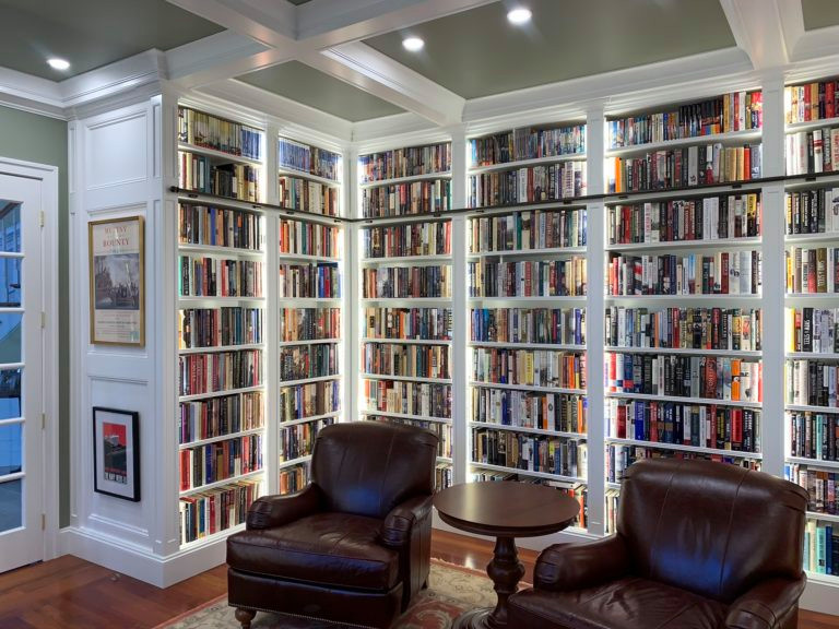 На фото: домашняя библиотека среднего размера в классическом стиле с зелеными стенами, паркетным полом среднего тона, оранжевым полом, кессонным потолком и панелями на части стены с