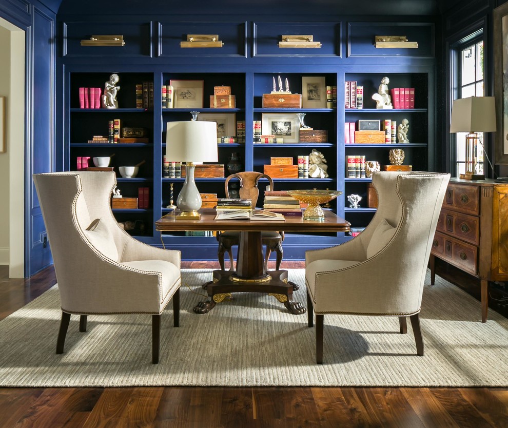 Modelo de despacho tradicional de tamaño medio con biblioteca, paredes azules, suelo de madera en tonos medios y escritorio independiente