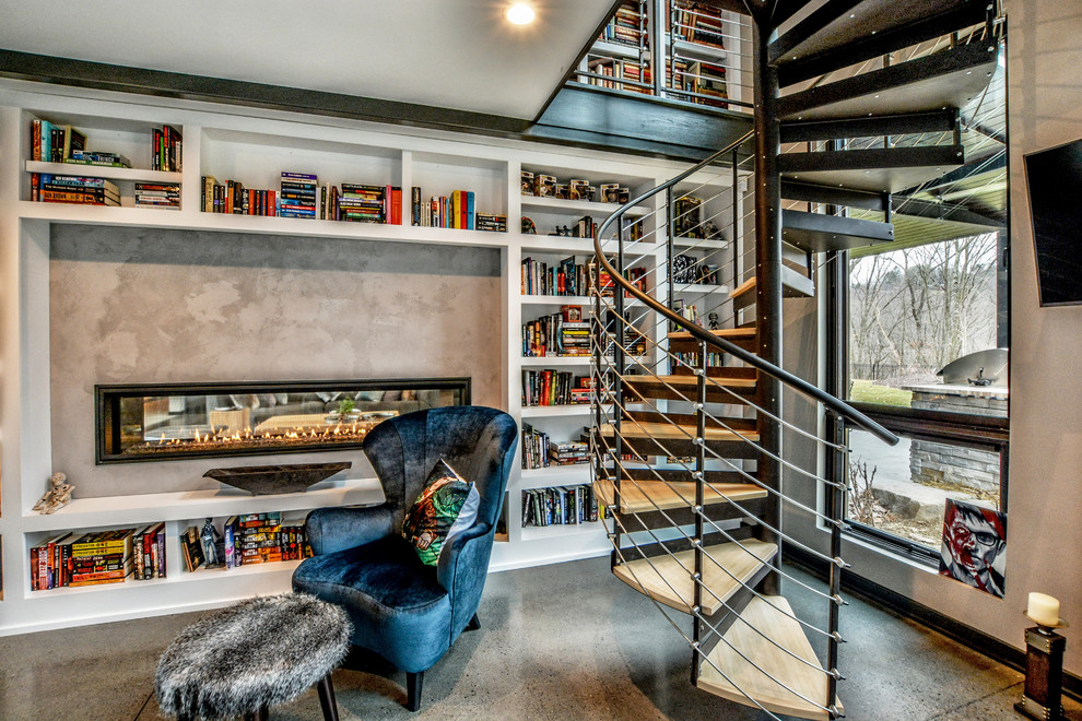 Foto på ett stort funkis arbetsrum, med ett bibliotek, beige väggar, betonggolv, en dubbelsidig öppen spis, en spiselkrans i betong, beiget golv och ett fristående skrivbord