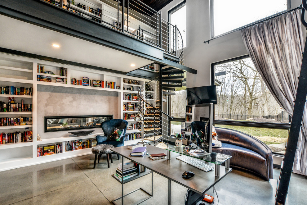 Идея дизайна: большой домашняя библиотека в современном стиле с бежевыми стенами, бетонным полом, двусторонним камином, фасадом камина из бетона, отдельно стоящим рабочим столом и бежевым полом