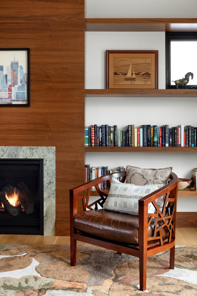 Geräumiges Lesezimmer mit weißer Wandfarbe, hellem Holzboden, Kamin, Kaminumrandung aus Holz und braunem Boden in Baltimore