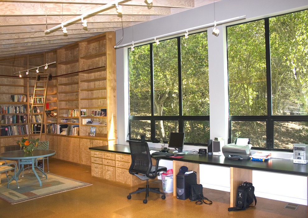 Cette image montre un petit bureau minimaliste de type studio avec un mur blanc, un sol en liège et un bureau intégré.