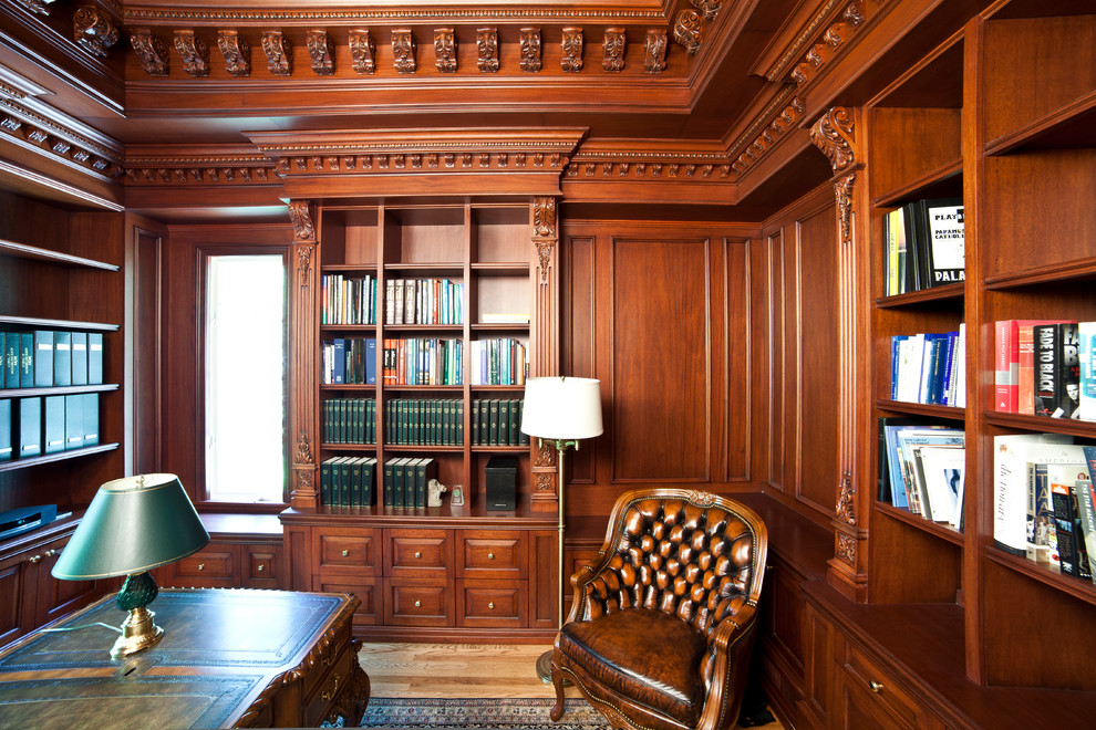 Foto på ett mellanstort vintage hemmabibliotek, med bruna väggar, mellanmörkt trägolv, ett fristående skrivbord och brunt golv