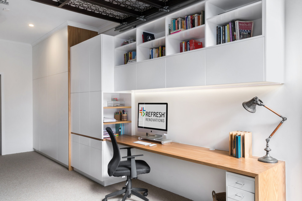 Modernes Arbeitszimmer ohne Kamin mit Arbeitsplatz, weißer Wandfarbe, Einbau-Schreibtisch und braunem Boden in Sonstige