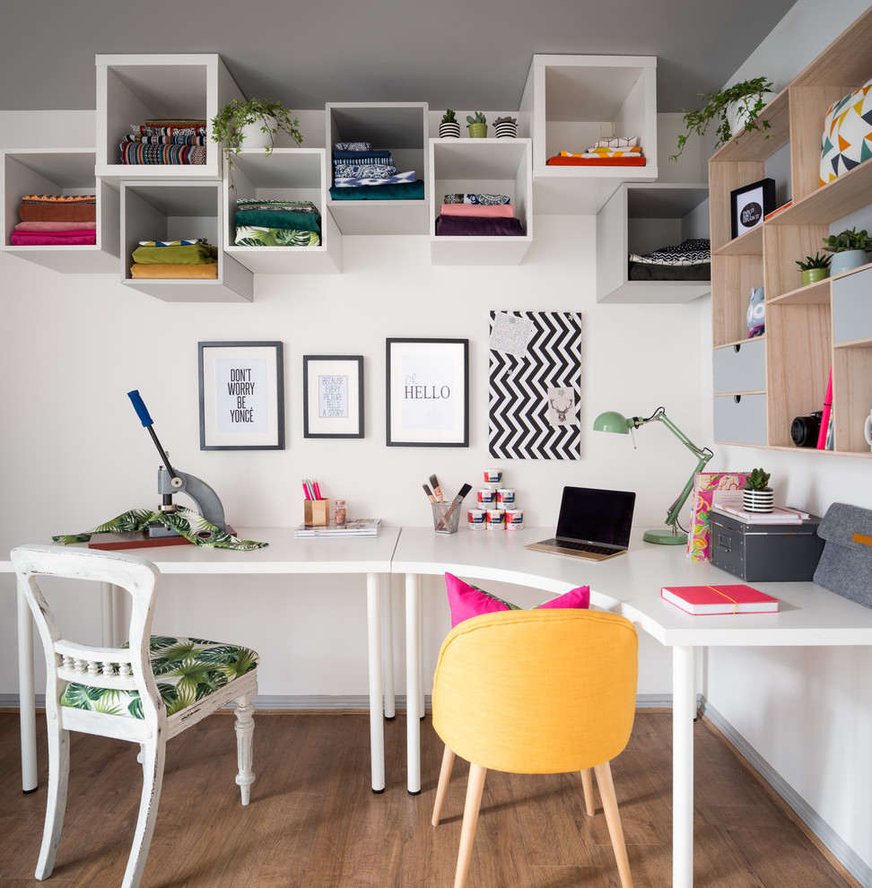 Photo of a medium sized eclectic home studio in Edinburgh with white walls, laminate floors, no fireplace, a freestanding desk and brown floors.