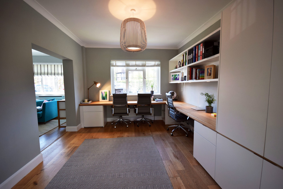 Esempio di un grande ufficio minimal con pareti grigie, pavimento in legno massello medio, scrivania incassata e pavimento marrone