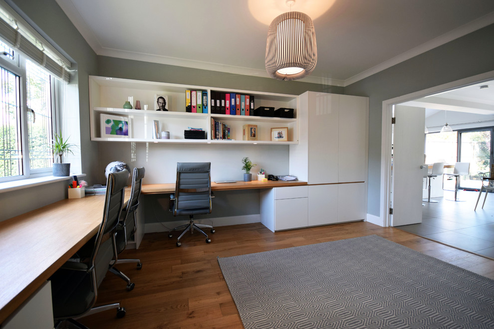 Idées déco pour un grand bureau contemporain avec un mur gris, un sol en bois brun, un bureau intégré et un sol marron.