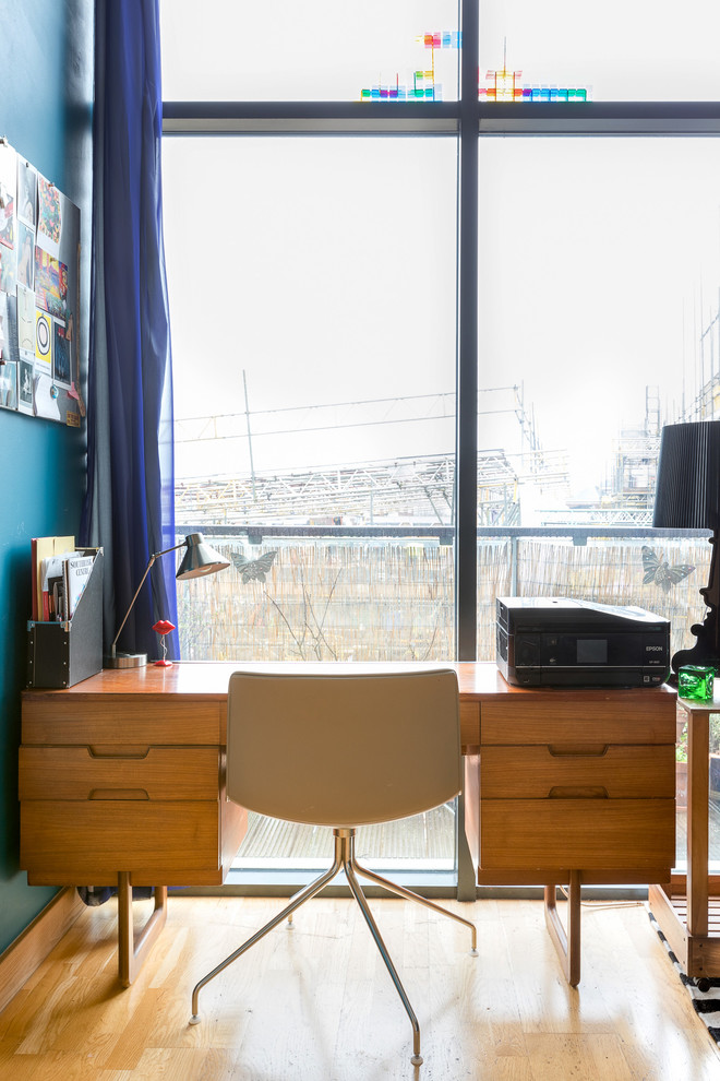 Ejemplo de despacho moderno pequeño con paredes azules, suelo de madera clara, escritorio independiente y suelo beige