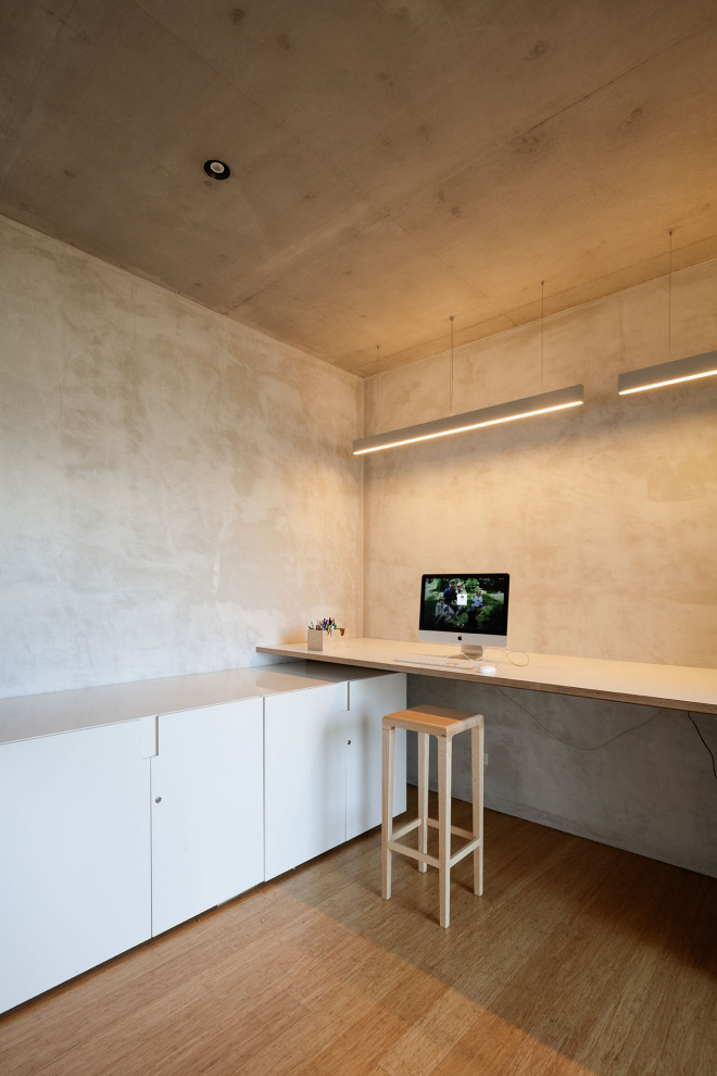 На фото: рабочее место среднего размера в стиле модернизм с серыми стенами, полом из бамбука, встроенным рабочим столом и бежевым полом