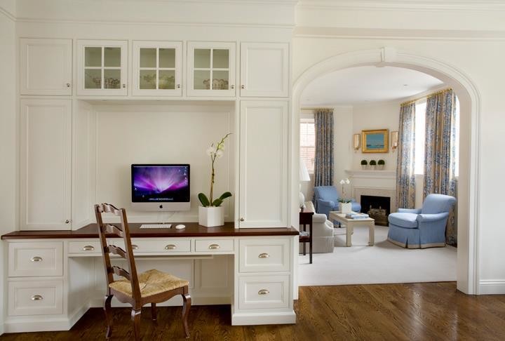 Kleines Klassisches Arbeitszimmer ohne Kamin mit Arbeitsplatz, weißer Wandfarbe, braunem Holzboden, Einbau-Schreibtisch und braunem Boden