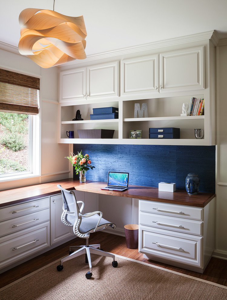 Modelo de despacho clásico renovado con paredes azules, escritorio empotrado y suelo de madera oscura