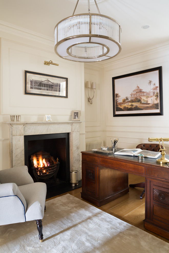 Design ideas for a medium sized classic study in London with white walls, medium hardwood flooring, a standard fireplace, a stone fireplace surround, a freestanding desk and brown floors.