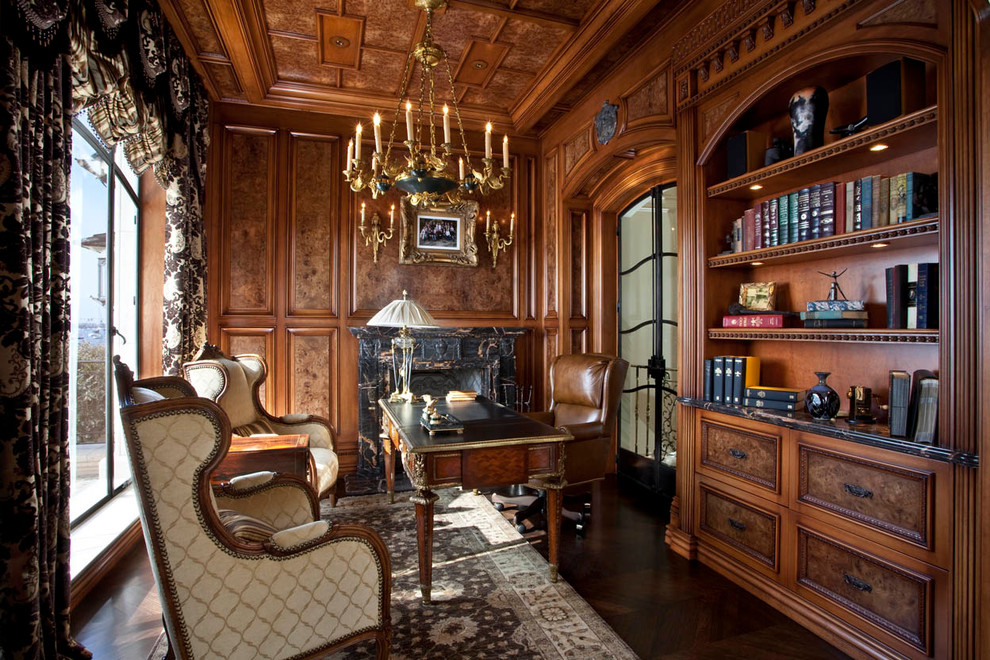 На фото: кабинет в классическом стиле с темным паркетным полом, стандартным камином и отдельно стоящим рабочим столом с