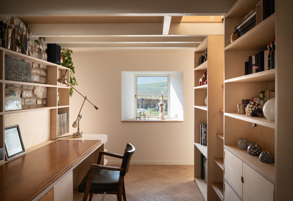 Kleines Nordisches Arbeitszimmer ohne Kamin mit Arbeitsplatz, weißer Wandfarbe, hellem Holzboden, Einbau-Schreibtisch, braunem Boden und freigelegten Dachbalken in London