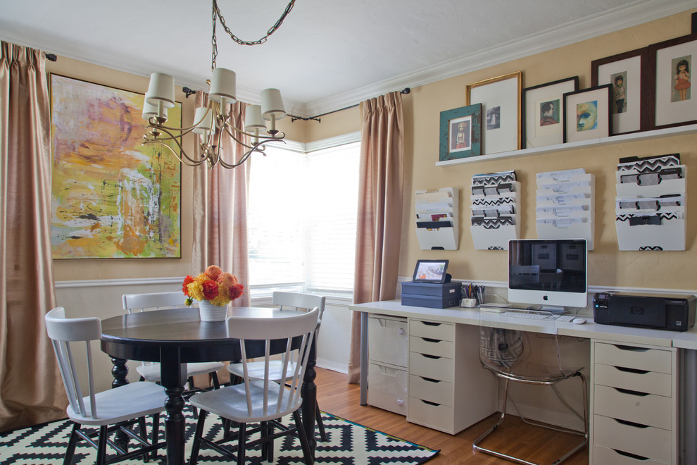 Inredning av ett klassiskt mellanstort arbetsrum, med gula väggar, mellanmörkt trägolv och ett inbyggt skrivbord