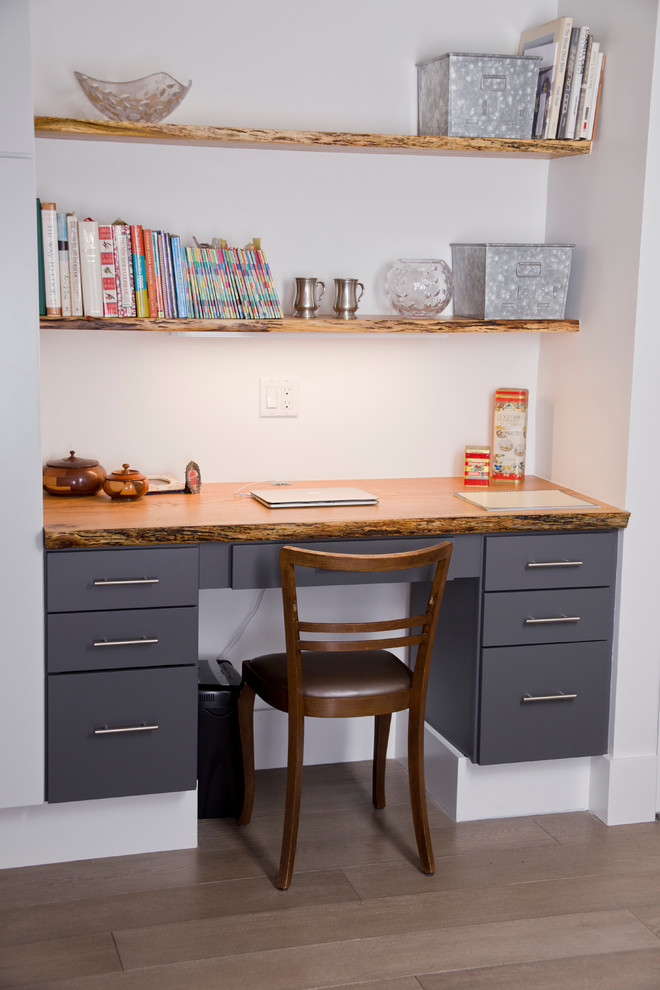 Kleines Rustikales Arbeitszimmer ohne Kamin mit Arbeitsplatz, weißer Wandfarbe, braunem Holzboden und Einbau-Schreibtisch in New York