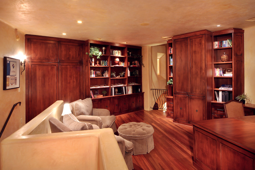 Modelo de despacho tradicional de tamaño medio sin chimenea con paredes beige, suelo de madera oscura, escritorio independiente y suelo marrón