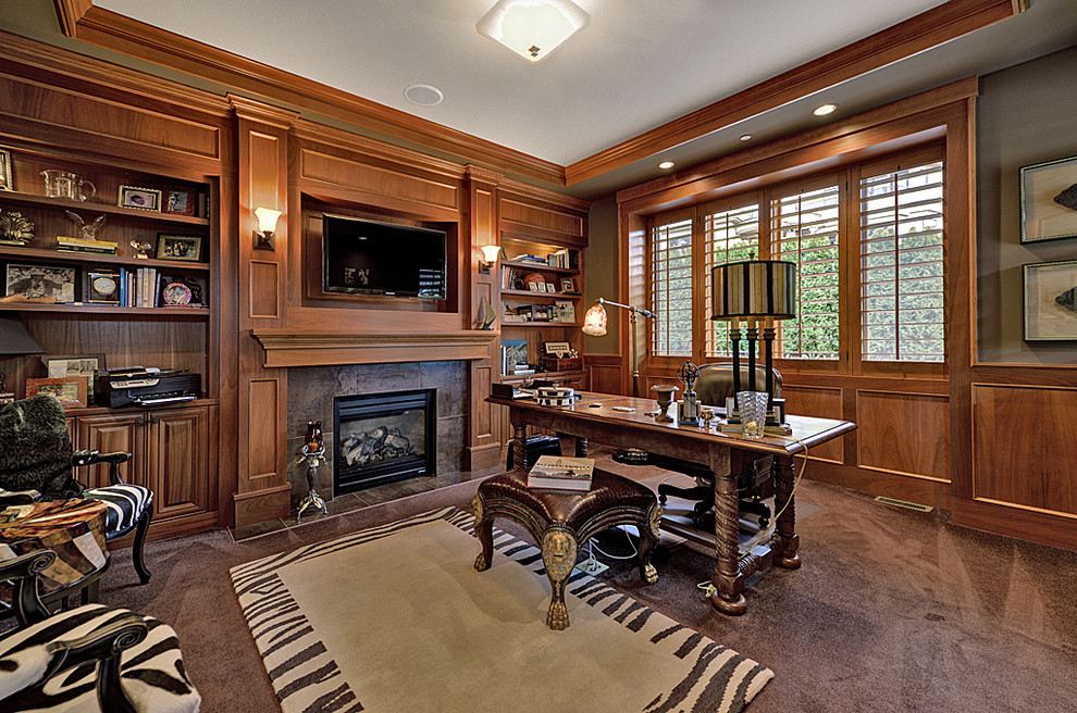 This is an example of a large classic study in Seattle with green walls, carpet, a standard fireplace, a tiled fireplace surround, a freestanding desk and brown floors.
