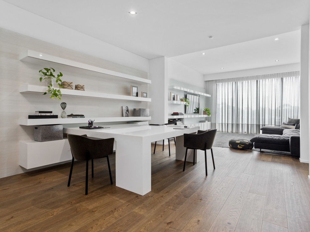 Modernes Arbeitszimmer mit weißer Wandfarbe, braunem Holzboden, Einbau-Schreibtisch und braunem Boden in Perth