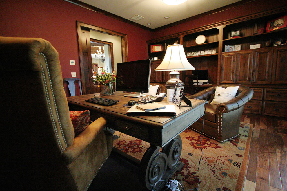 Uriges Arbeitszimmer mit roter Wandfarbe, braunem Holzboden und freistehendem Schreibtisch in Kansas City